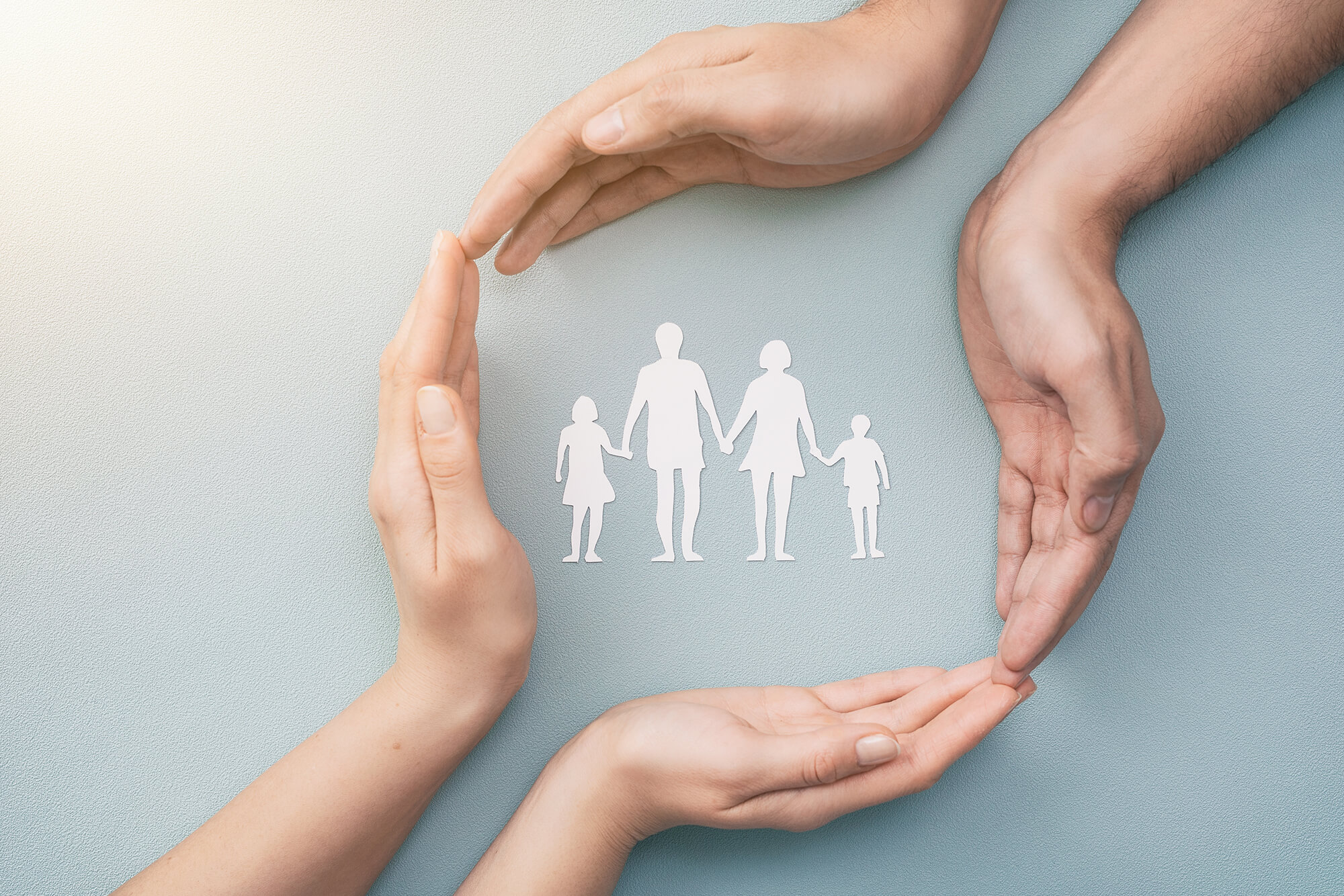 Family care concept. Hands with paper silhouette on table.